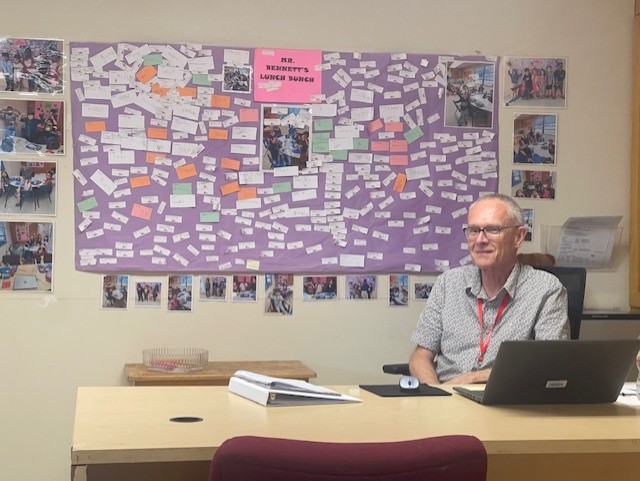 Mr. Bennett next to his wall of Lunch Bunch memories