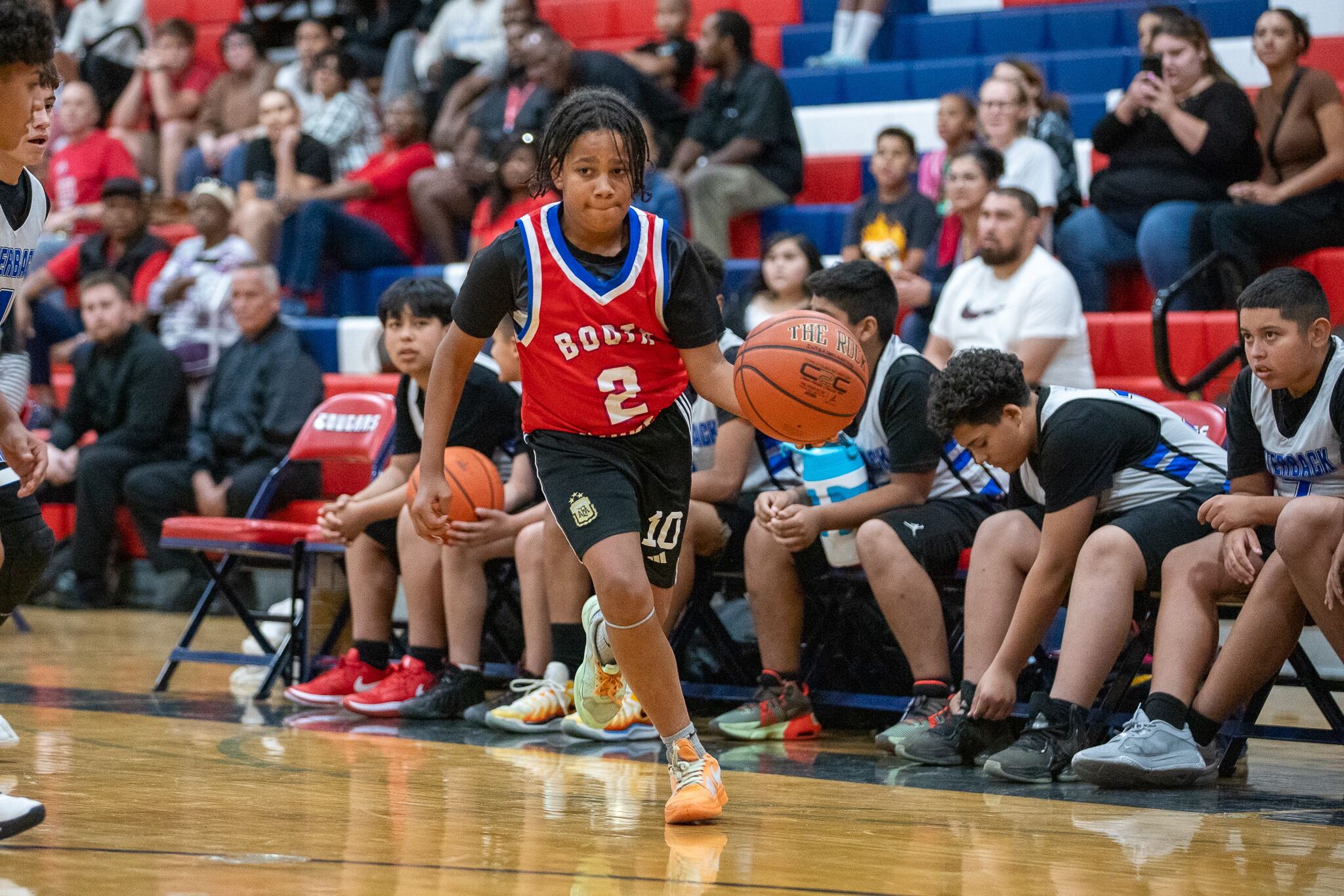 A boy dribbles a basketball down the court