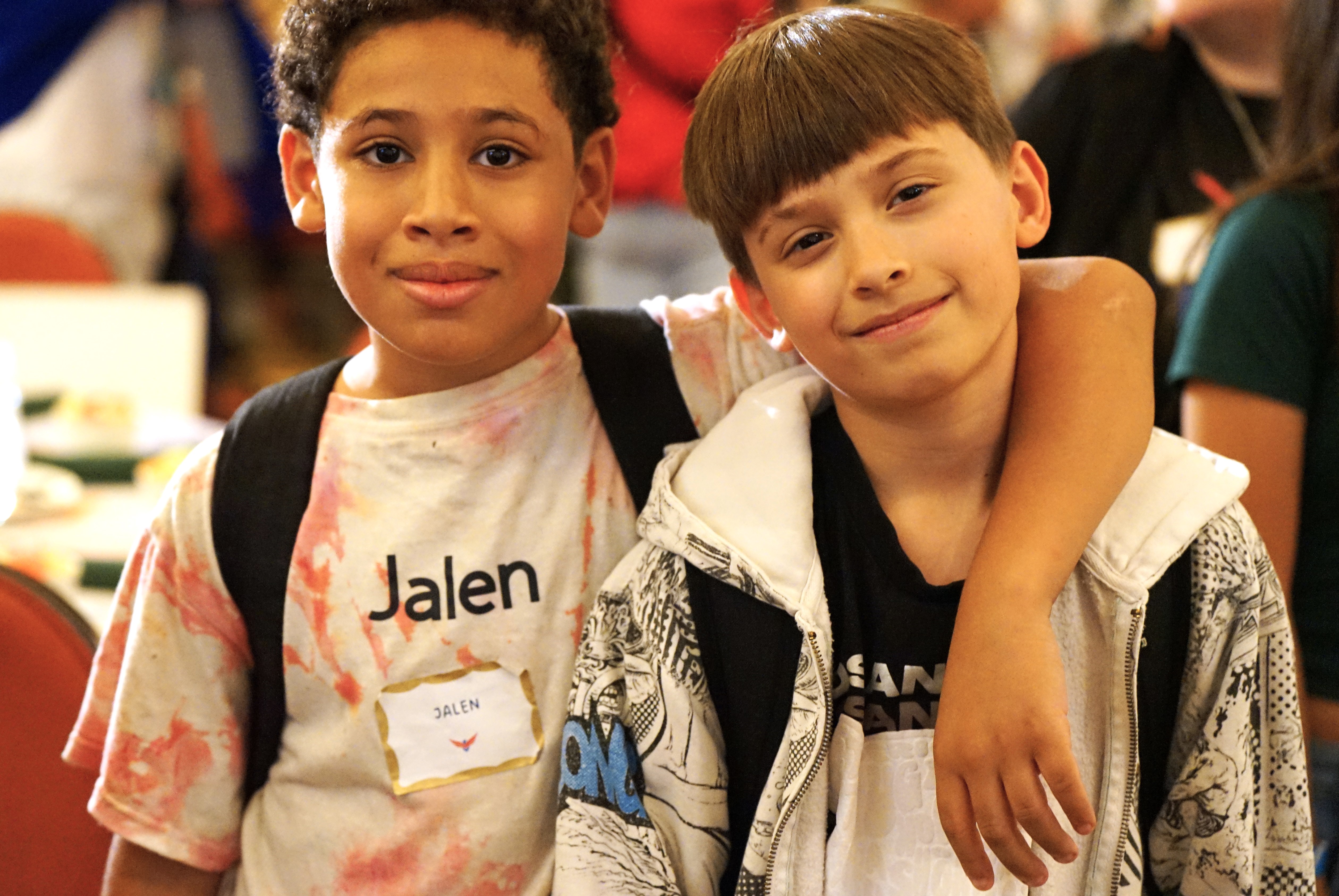 Two boys smile with their arms over each other's shoulders