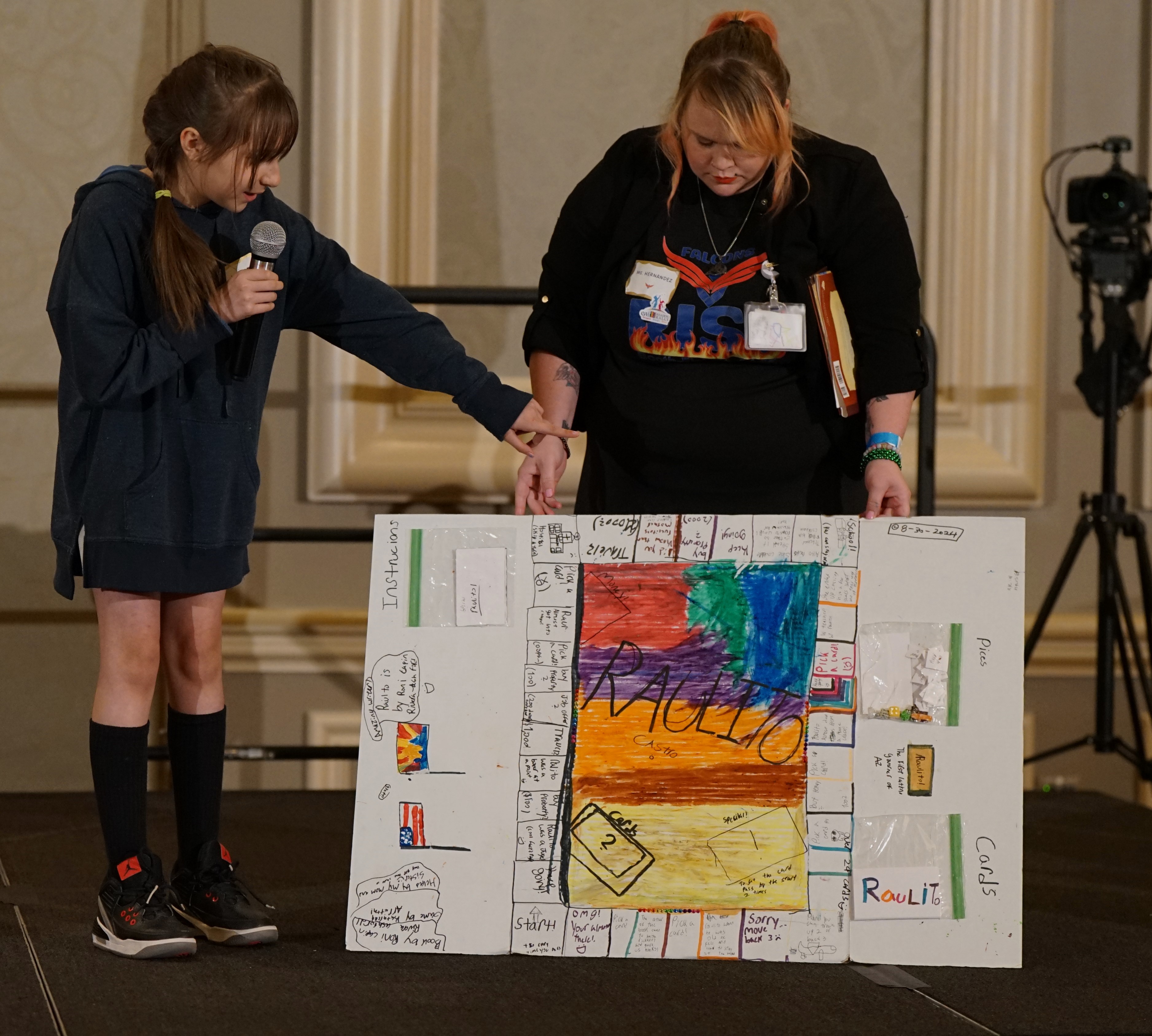 A girl presents her poster up on stage with an EWI member