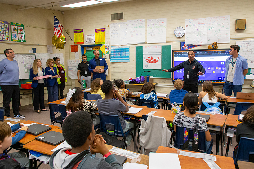 Two men stand at the front of a classroom of students