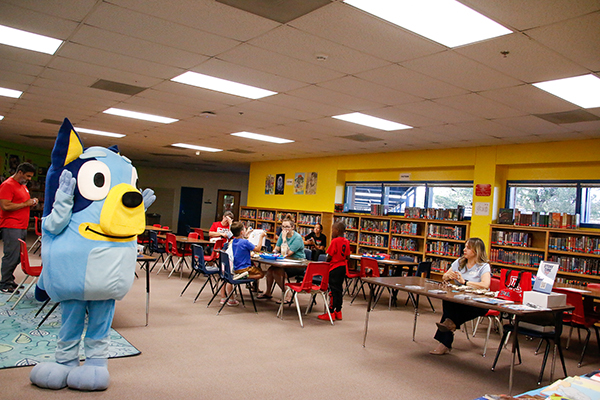 A person dressed in a Bluey costume hangs out in the library during Literacy Night
