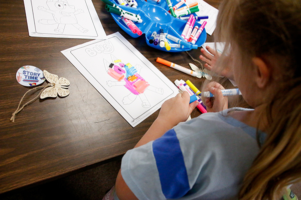 A girl colors a picture of Bluey