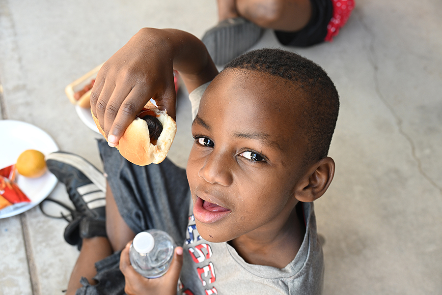 A little boy holds up a hot dog
