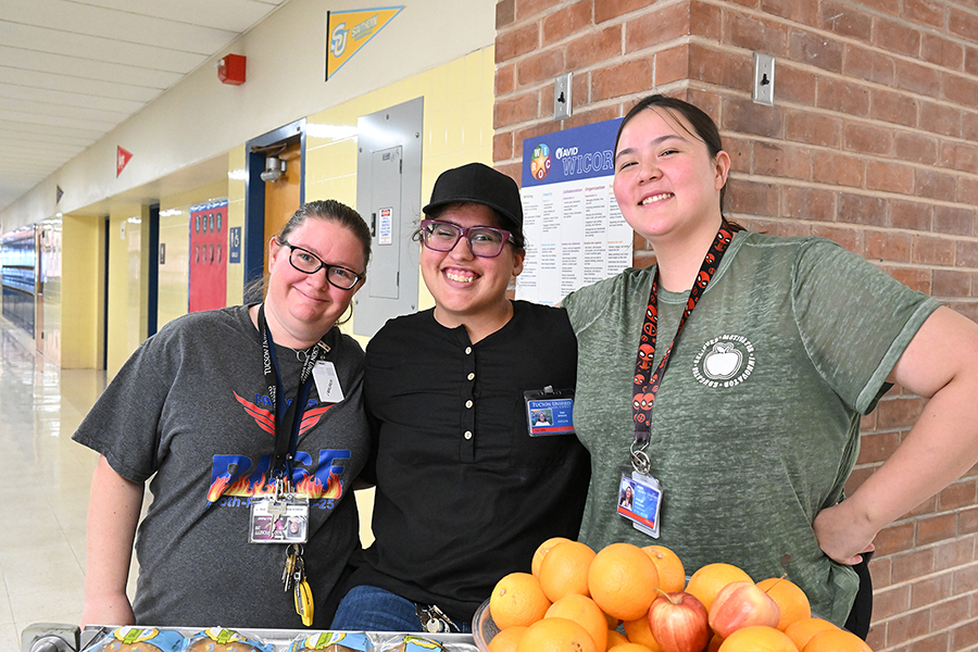 Three women smile in the school hallway
