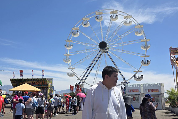 A preteen boy walks in front of the ferris wheel