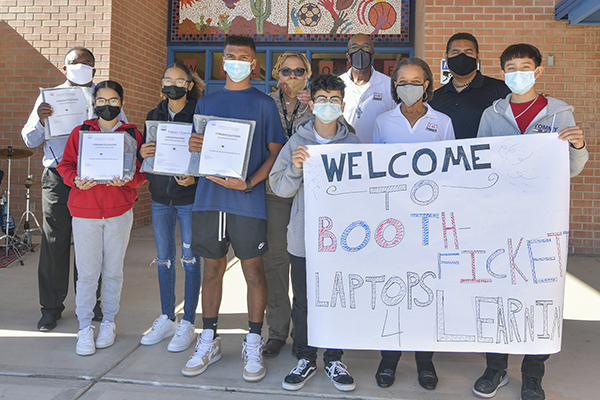 Students holding laptops and a sign that says welcome to Booth Fickett Laptops for Learning
